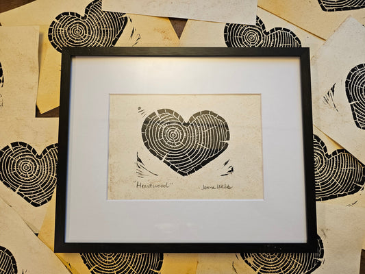 Framed artwork of a heart-shaped tree ring design on a textured surface.